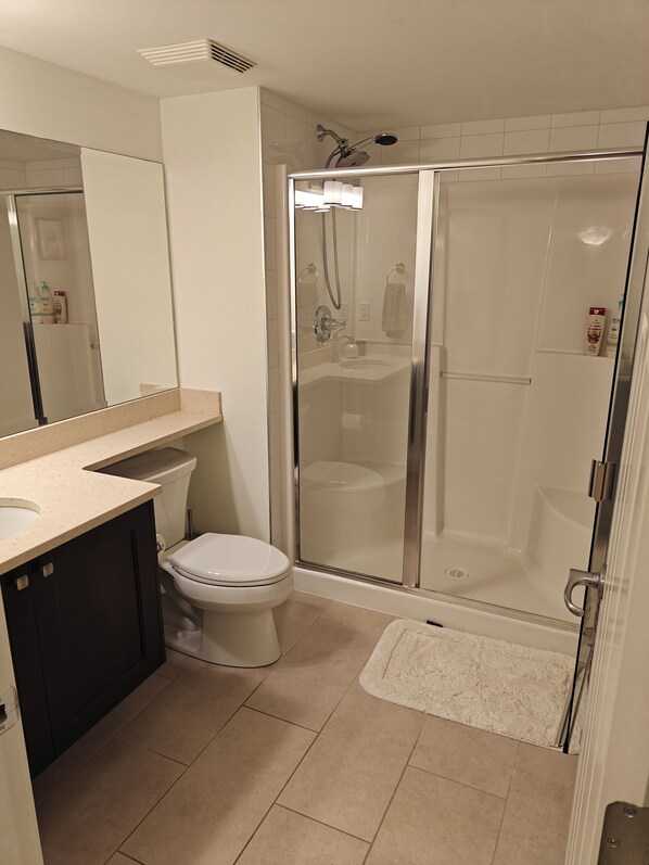 A modern bathroom with a glass-enclosed shower, a toilet, and a sink.