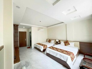 Habitación de hotel con dos camas, un armario de madera, un ventilador y un ventilador de techo.
