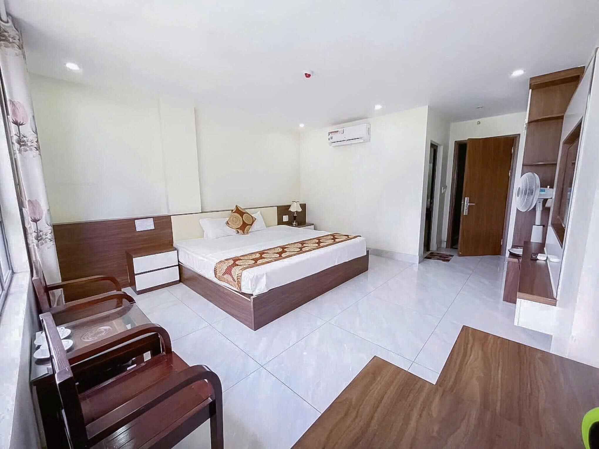 A hotel room with a bed, bedside table, chair, and a small desk with a chair.