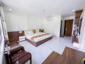 Una camera d'albergo con un letto, un comodino, una sedia e una piccola scrivania con una sua seduta.
