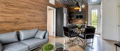 Una sala de estar moderna con un sofá, una mesa de centro de vidrio y un tapete de cuero de vaca.