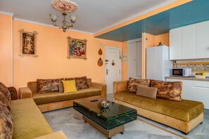 Ein Wohnzimmer mit zwei Sofas, einem Couchtisch, einer Tür und einem Küchenbereich.