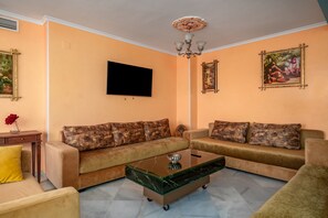 Ein Wohnzimmer mit zwei Sofas, einem Couchtisch, einem Flachbildfernseher und Wanddekoration.