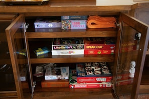 Ein Holzschrank mit verschiedenen Gesellschaftsspielen und Puzzles.