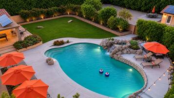 A backyard with a swimming pool, outdoor furniture, and a well-maintained lawn.