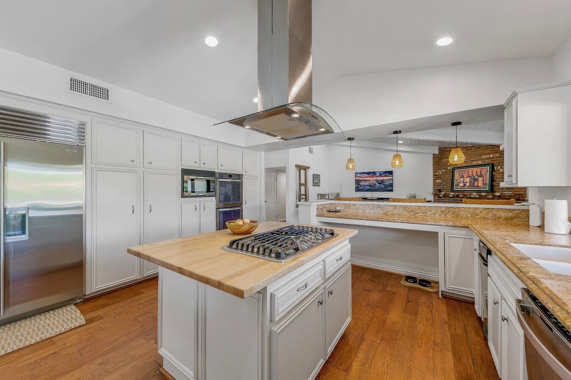 A modern kitchen with white cabinetry, stainless steel appliances, and a central island.