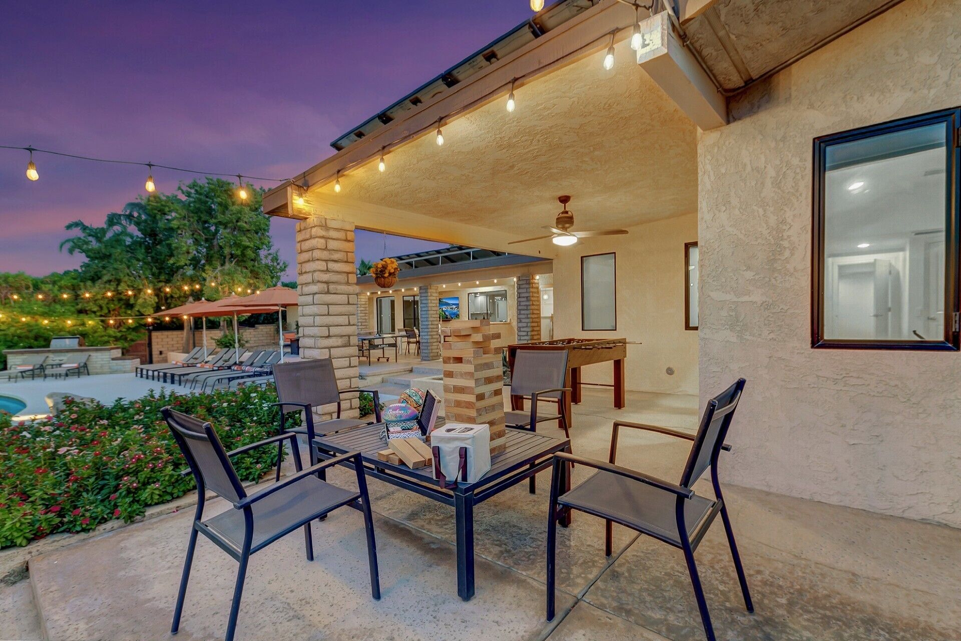 An outdoor patio area with a pool, seating, and a table with chairs.
