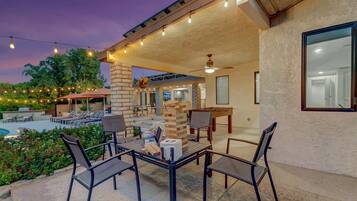 An outdoor patio area with a pool, seating, and a table with chairs.