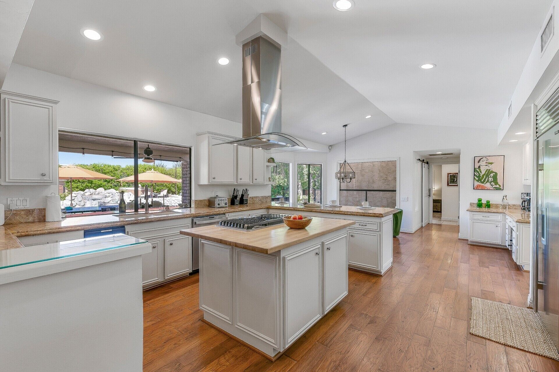 A spacious kitchen with a large island, white cabinetry, and a view to an outdoor area.