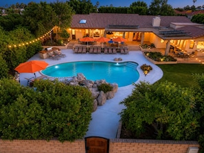 A residential property with a swimming pool, outdoor seating, and a well-lit patio area.