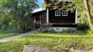 Una baita rustica con facciata in legno, un vialetto in pietra che conduce all'ingresso e un prato.