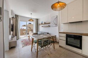 Eine moderne Küche mit Esstisch, Stühlen, einem eingebauten Ofen und einem großen Fenster.