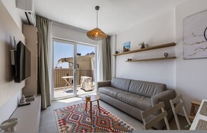 Ein modernes Wohnzimmer mit einer Couch, einem Fernseher, einem gemusterten Teppich und einem Balkon mit Blick.
