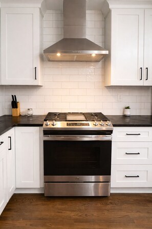 A kitchen with white cabinets, a stainless steel range, and a black countertop. - Cozy Home in East Atlanta (Atlanta)
