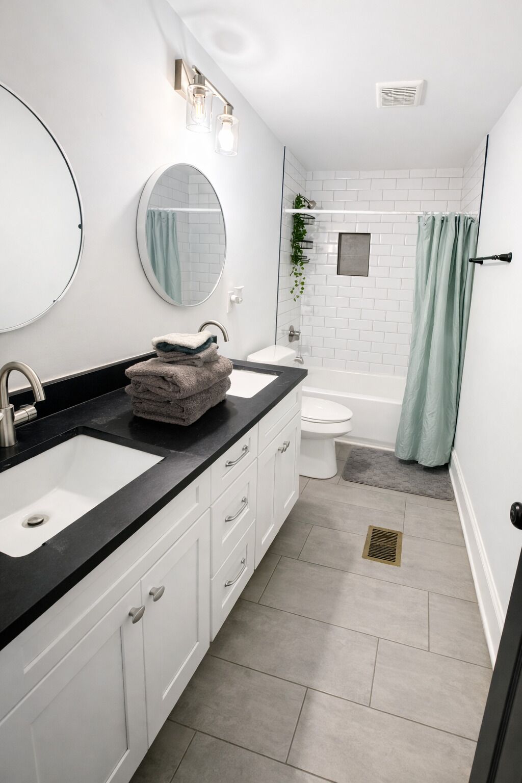 A modern bathroom with two sinks, a toilet, a shower, and a mirror.