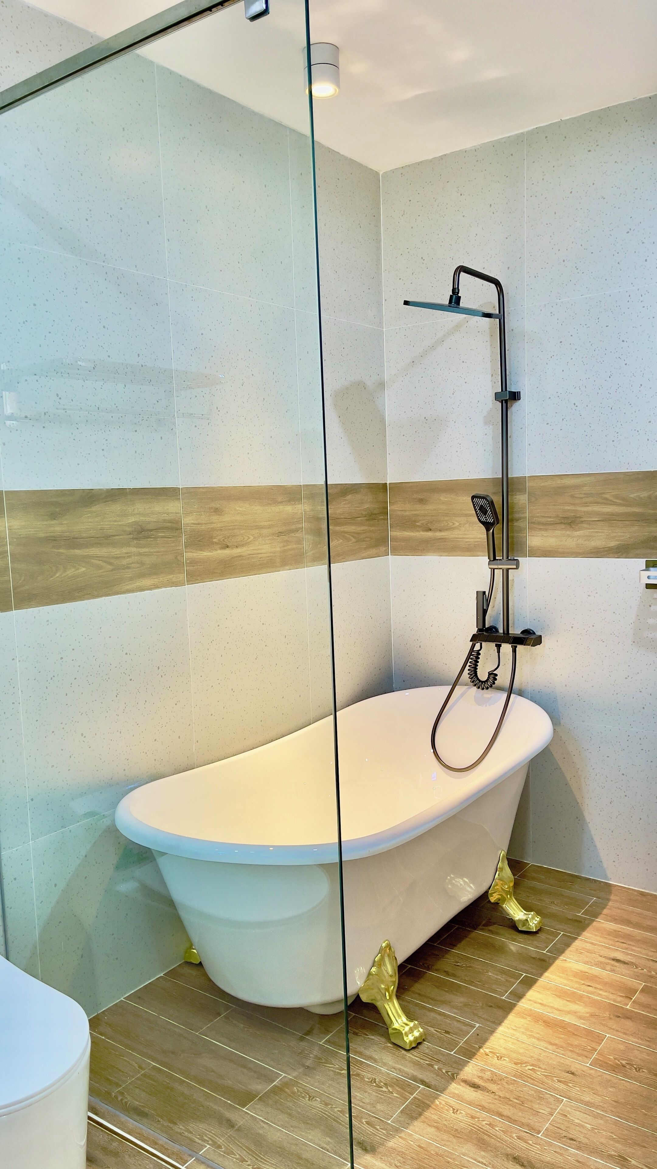 A modern bathroom with a freestanding bathtub, a glass shower enclosure, and a wooden floor.
