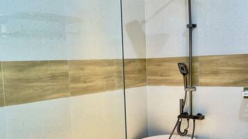 A modern bathroom with a freestanding bathtub, a glass shower enclosure, and a wooden floor.