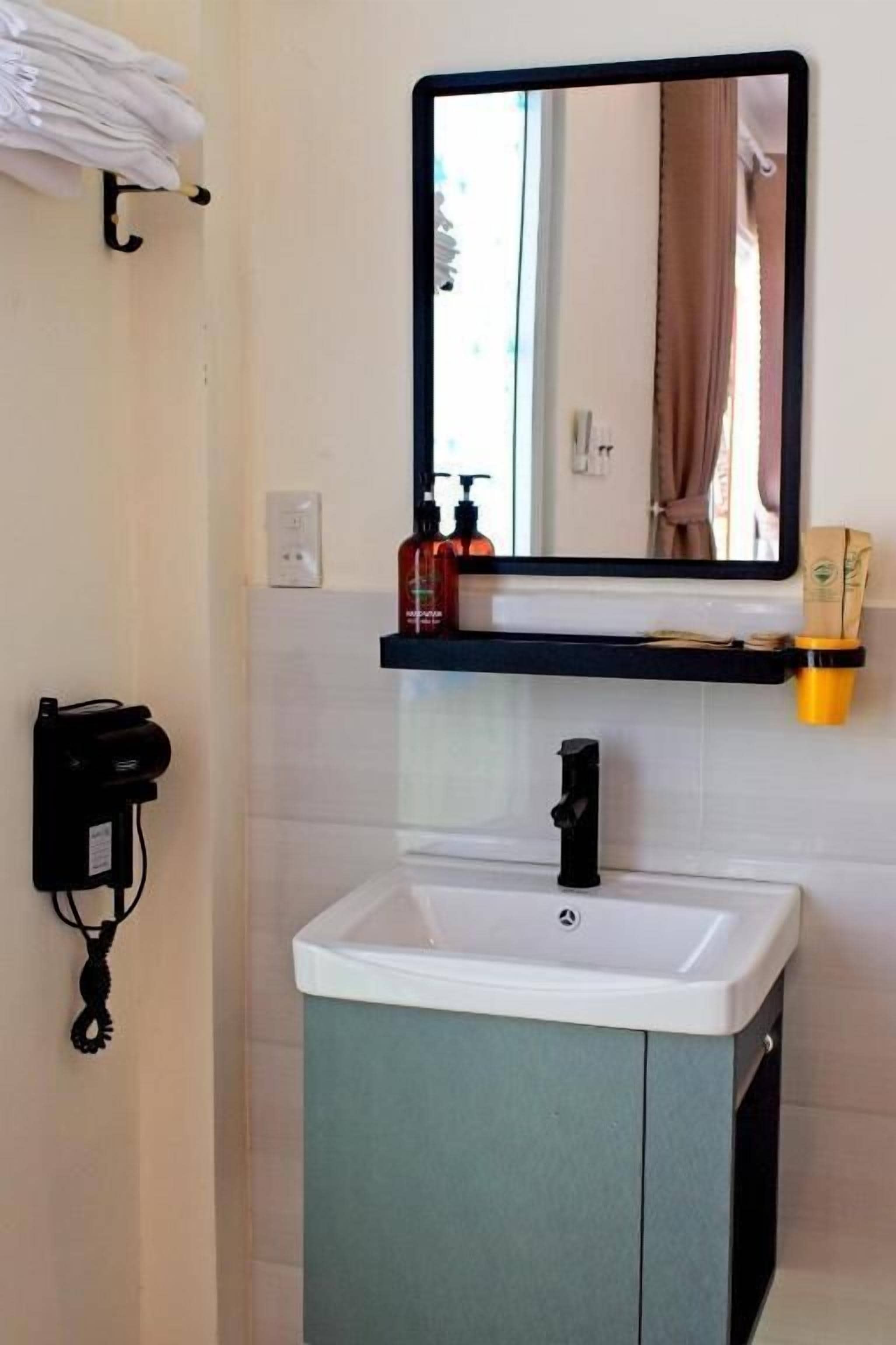 A bathroom with a white sink, a black faucet, a mirror above the sink, and a towel rack on the wall.
