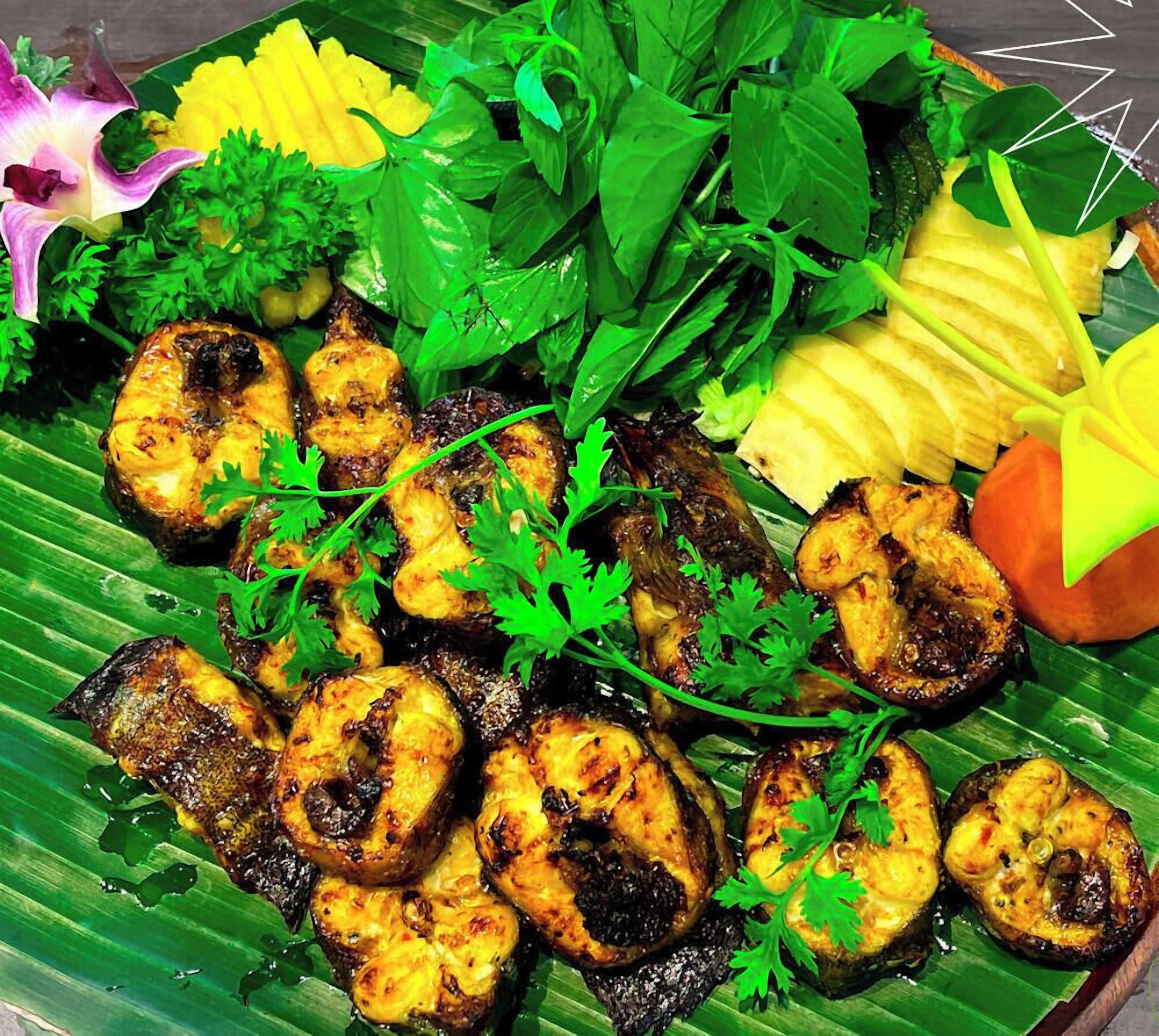 Un plato de pollo a la parrilla y verduras sobre una hoja de plátano.