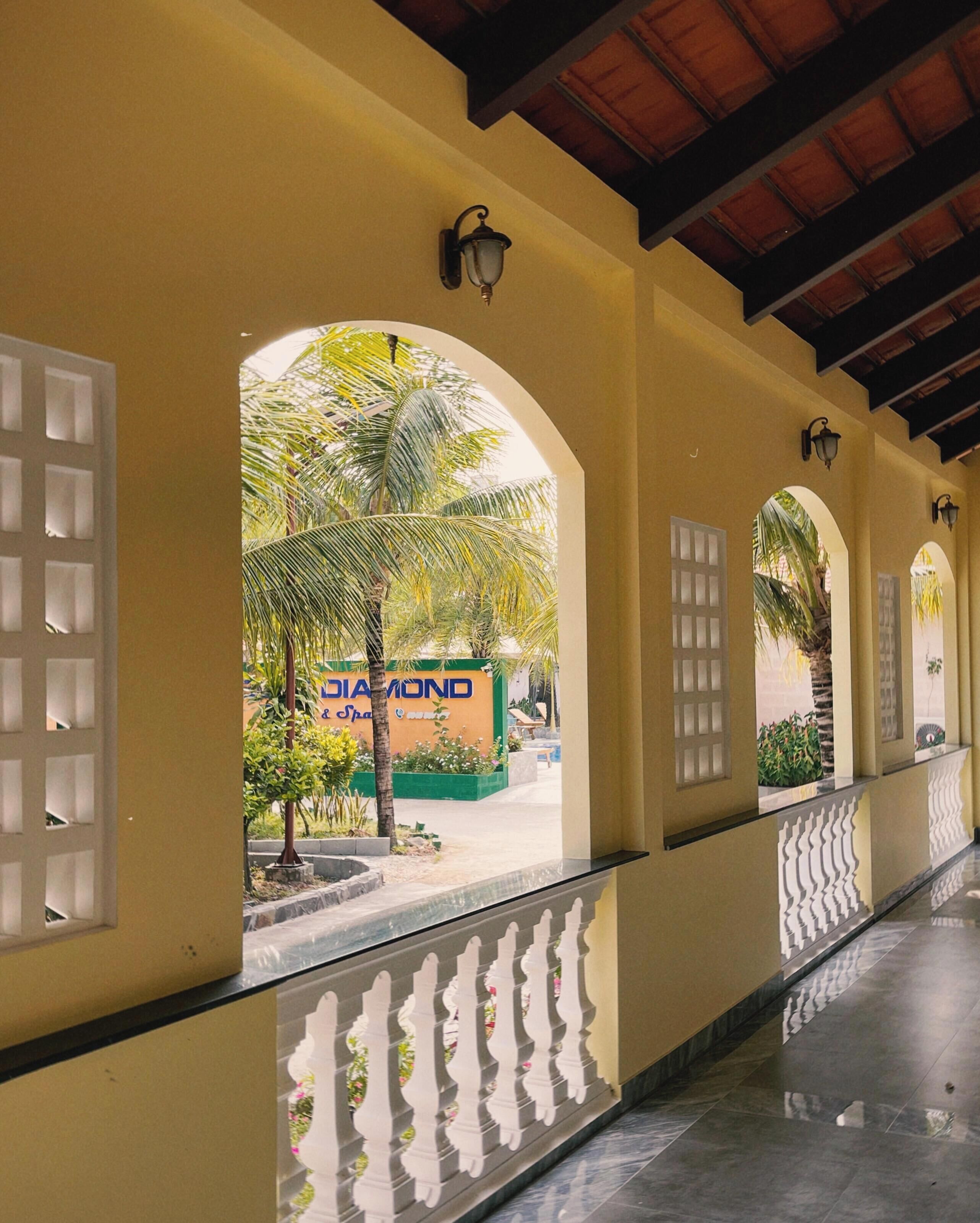A corridor with arched doorways, a tiled floor, and a view of a building with a sign that reads 'DIAMOND Spa & Sports'.