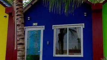 Un bâtiment bleu avec un palmier devant, une porte et une fenêtre.