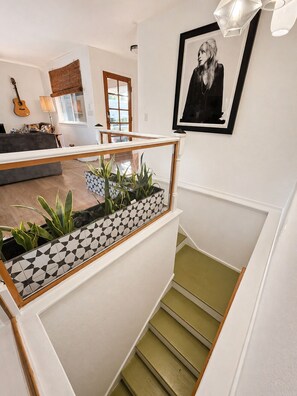A staircase with a geometric patterned railing, a framed portrait on the wall, and a guitar in the background. - Back40 Beehive: Bike-In Retreat-Trails, Lakes & Game Room (Bella Vista)