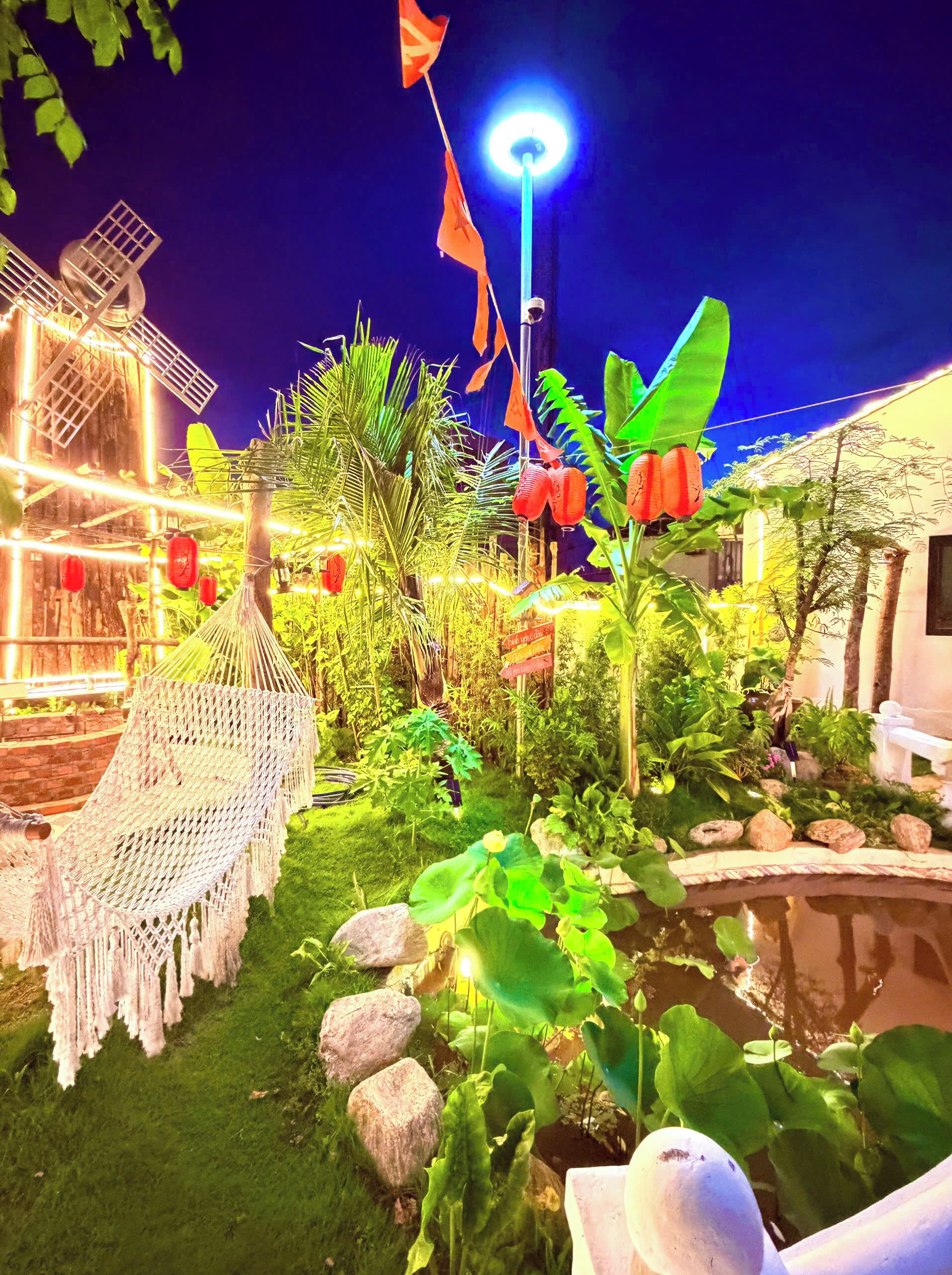 Un jardín con una hamaca, un estanque y un farol.