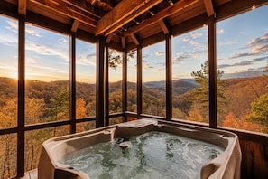 A hot tub in a wooden cabin with large windows overlooking a forested valley. - Epic Views! 2 King Suites, Hot Tub, Privacy, location, pool table! Has it all! (Sevierville)