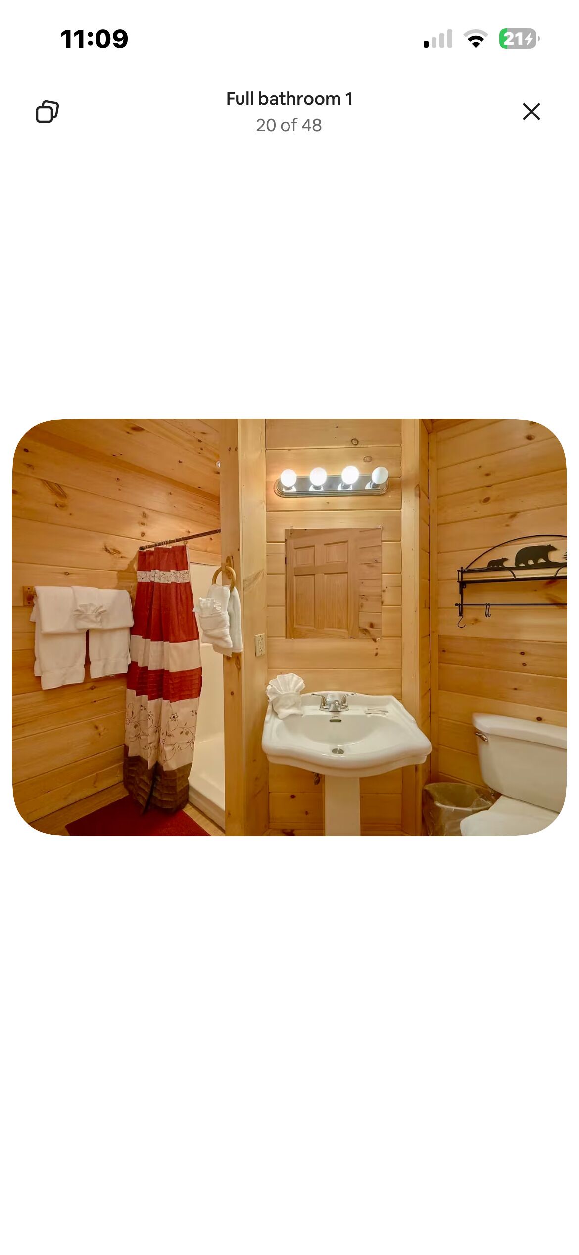 Een houten badkamer met een wastafel, toilet en handdoekhouder.
