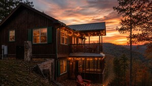 Eine Holzhütte mit Balkon, Feuerstelle und einem schönen Blick auf den Wald.