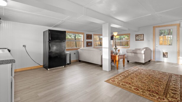 A spacious living area with a kitchen, a refrigerator, a sofa, a chair, and a rug. - Island Time Bungalow (Steinhatchee)