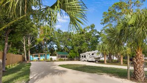 A campground with RVs, a small building, and palm trees. - Island Time Bungalow (Steinhatchee)