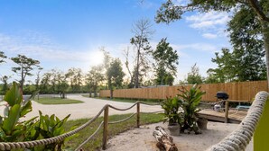 A fenced outdoor area with a sandy path, wooden deck, and potted plants. - Island Time Bungalow (Steinhatchee)