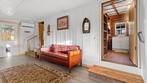 A spacious living room with a red leather sofa, a patterned rug, and a wooden bench. - Island Time Bungalow (Steinhatchee)