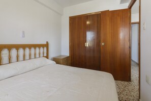 A bedroom with a wooden bed frame, a single bedside table, and a wardrobe.