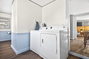A laundry room with a washing machine, dryer, and a shelf with folded towels.