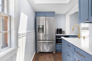A modern kitchen with a stainless steel refrigerator, built-in oven, and a white countertop.