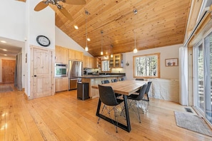 Une cuisine moderne avec un plancher en bois, un coin repas comprenant une table et des chaises, et une grande fenêtre offrant une vue sur l’extérieur.