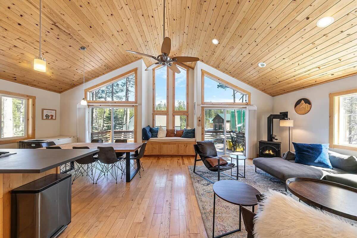 Une pièce spacieuse avec un plafond haut, de grandes fenêtres, une cheminée et un coin salon confortable.