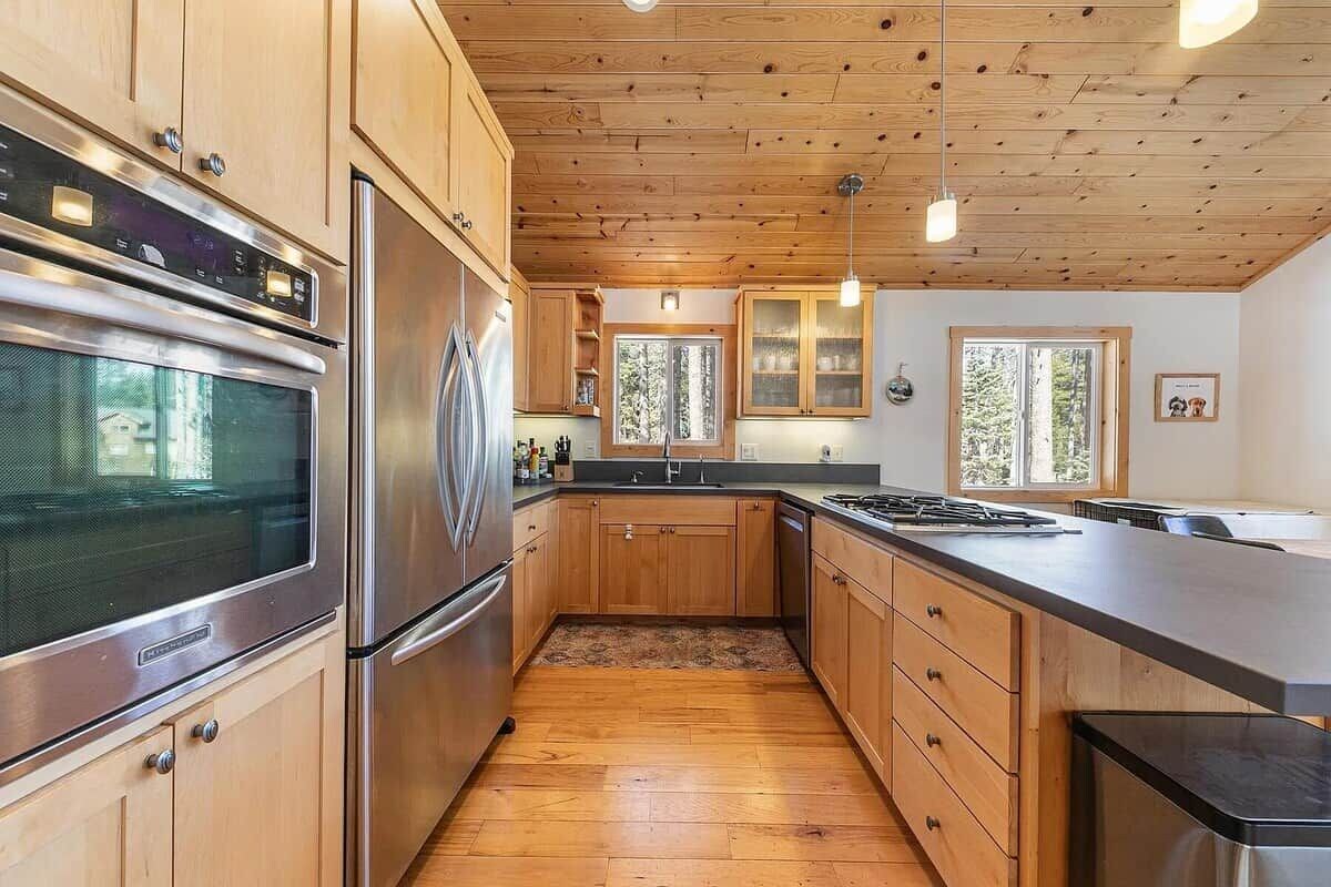 Une cuisine moderne avec des meubles en bois, des appareils électroménagers en acier inoxydable et un plancher en bois.