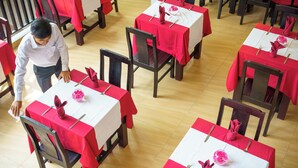 Ein Restaurant mit mehreren Tischen, jeder Tisch mit roter Tischdecke und Geschirr und Servietten gedeckt.