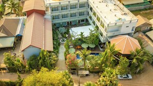 Ein mehrstöckiges Hotel mit Balkonen, einem Schwimmbad und üppiger Bepflanzung.