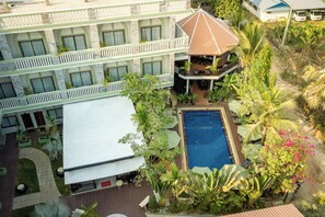 Ein mehrstöckiges Hotel mit Schwimmbad, Außenbereich und üppiger Bepflanzung.