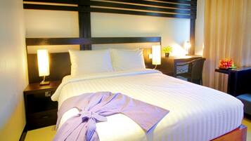 A hotel room with a bed, bedside lamps, a nightstand, a desk, and a chair.