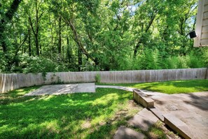 Ein Garten mit Holzzaun, Beton-Terrasse und einer Rasenfläche.