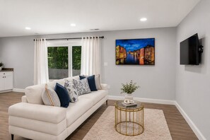 Ein Wohnzimmer mit einer Couch, einem runden Couchtisch, einem Gemälde und einem Fernseher.