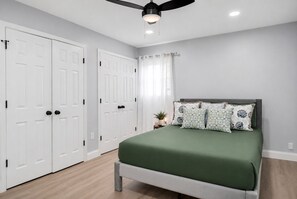 A bedroom with a bed, a ceiling fan, white double doors, and a window with curtains. - Luxury 6BR Retreat Near National Harbor & DC (Fort Washington)