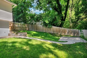 A backyard with a wooden fence, a concrete pathway, and a grassy lawn. - Luxury 6BR Retreat Near National Harbor & DC (Fort Washington)