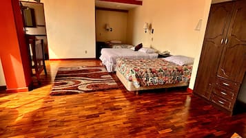 Quarto com piso de madeira, cama com roupa de cama floral, guarda-roupa e escrivaninha com luminária.