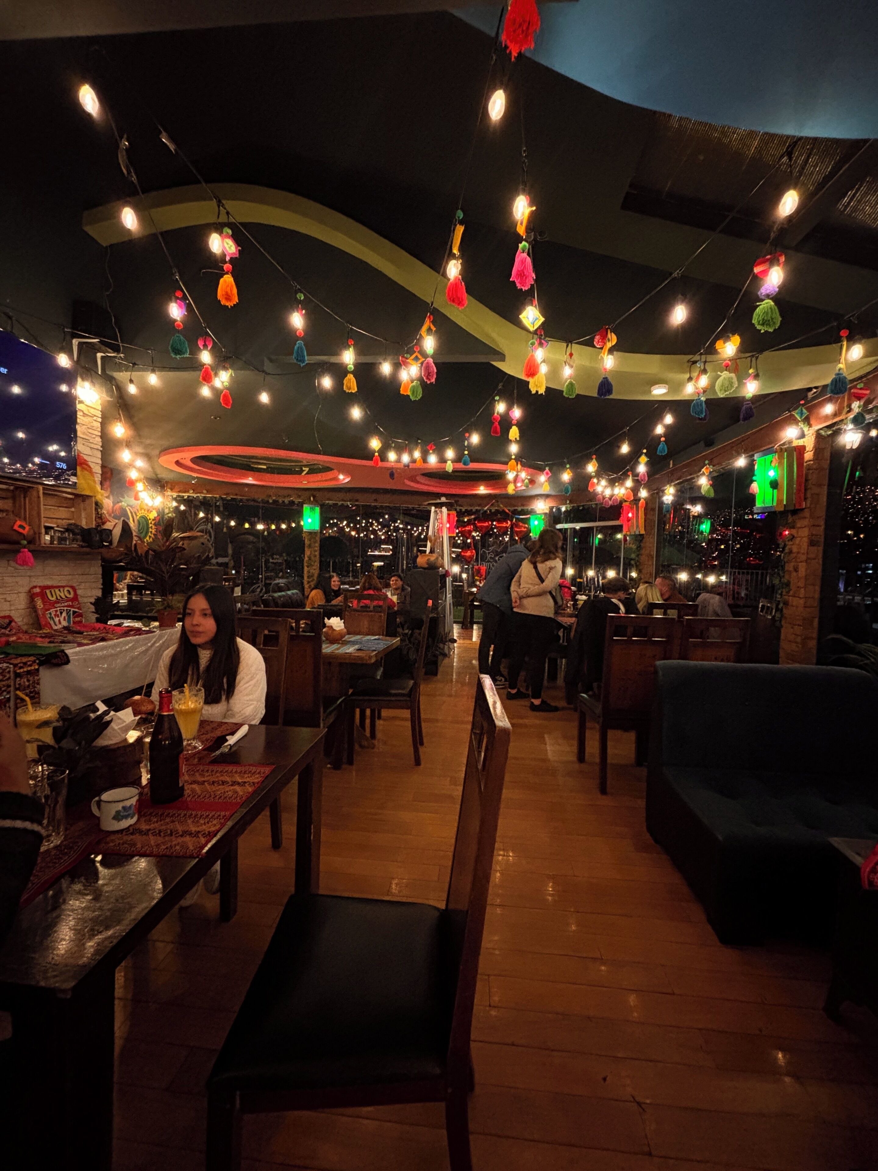 Un restaurant avec des tables, des chaises et des lampes suspendues.
